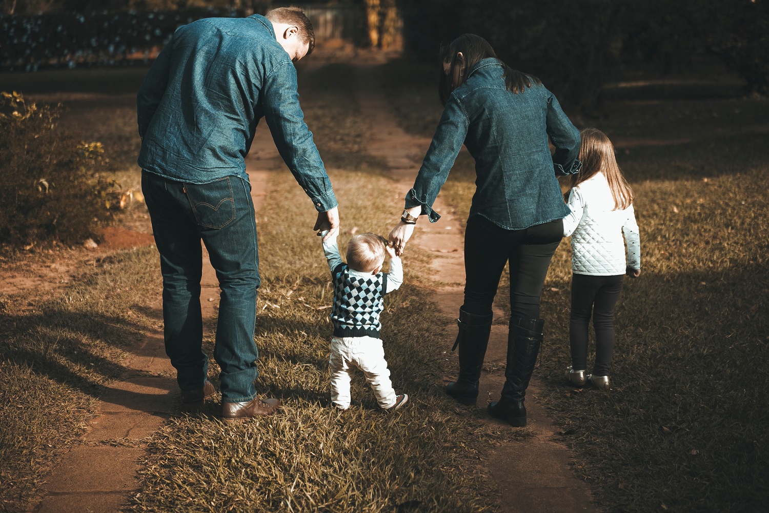 Two parents with two children all holding hands on a walk outside
